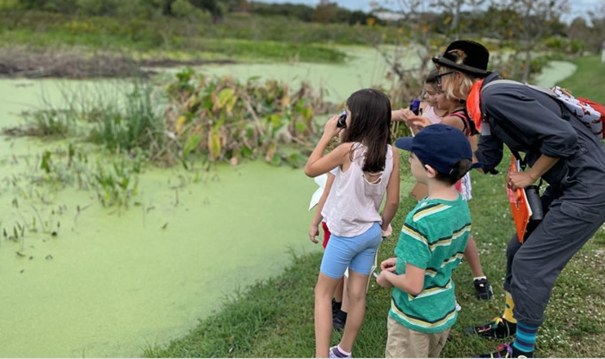 Kids looking for birds with binoculars at a pond